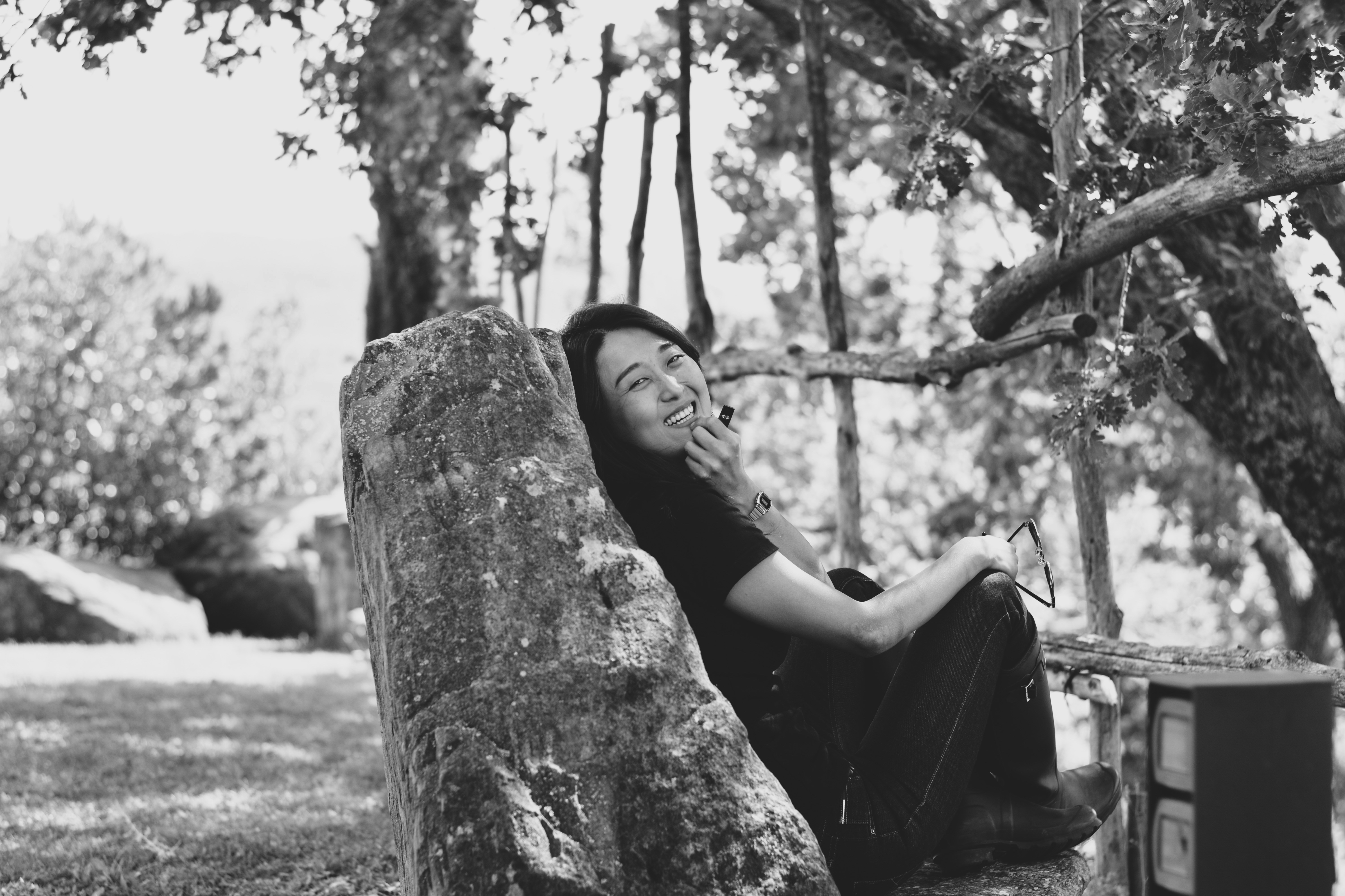 a woman sitting on a rock talking on a cell phone
