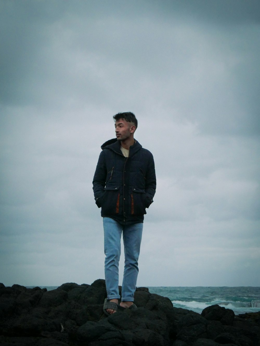 a man standing on a rock near the ocean