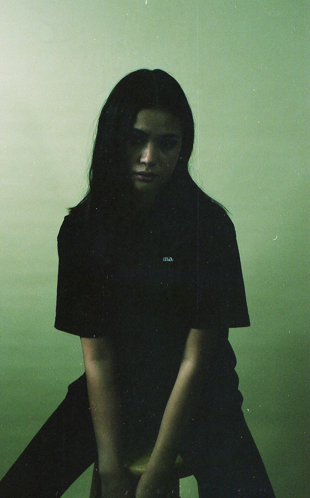 a woman sitting on a stool in a green room