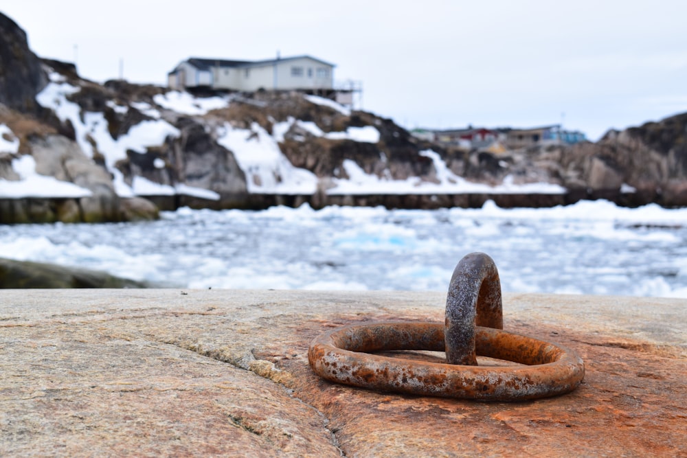 a rusted ring on a rock near a body of water