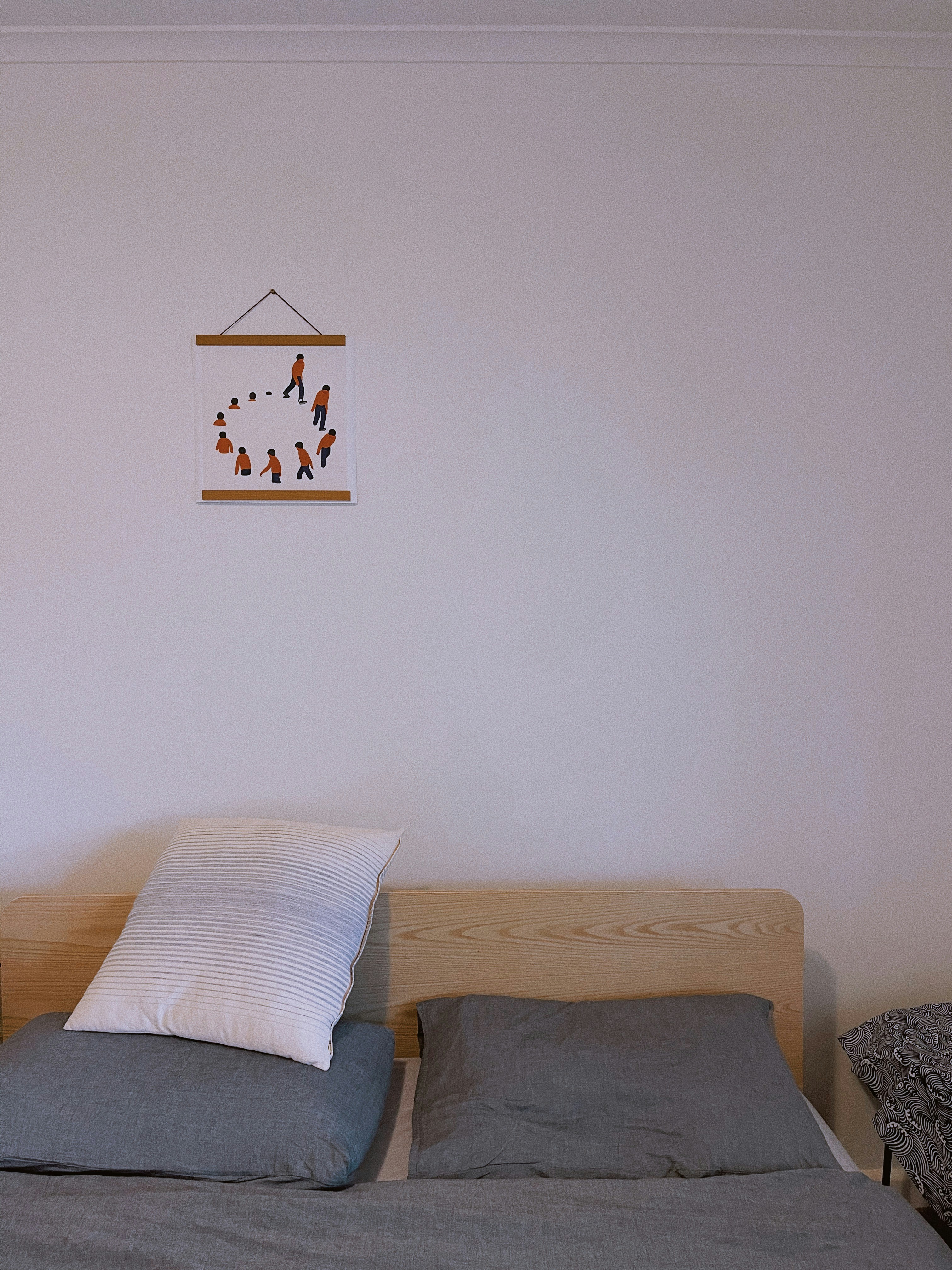 a bed with two pillows and a picture hanging on the wall