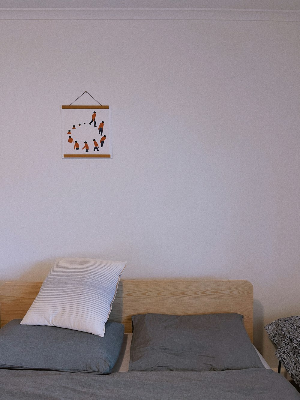 a bed with two pillows and a picture hanging on the wall