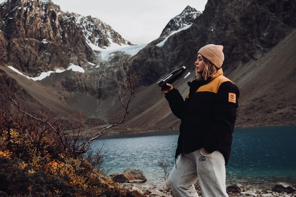 a man standing on top of a mountain next to a lake