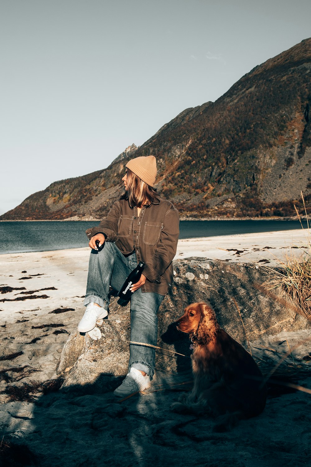 Un uomo seduto su una roccia accanto a un cane