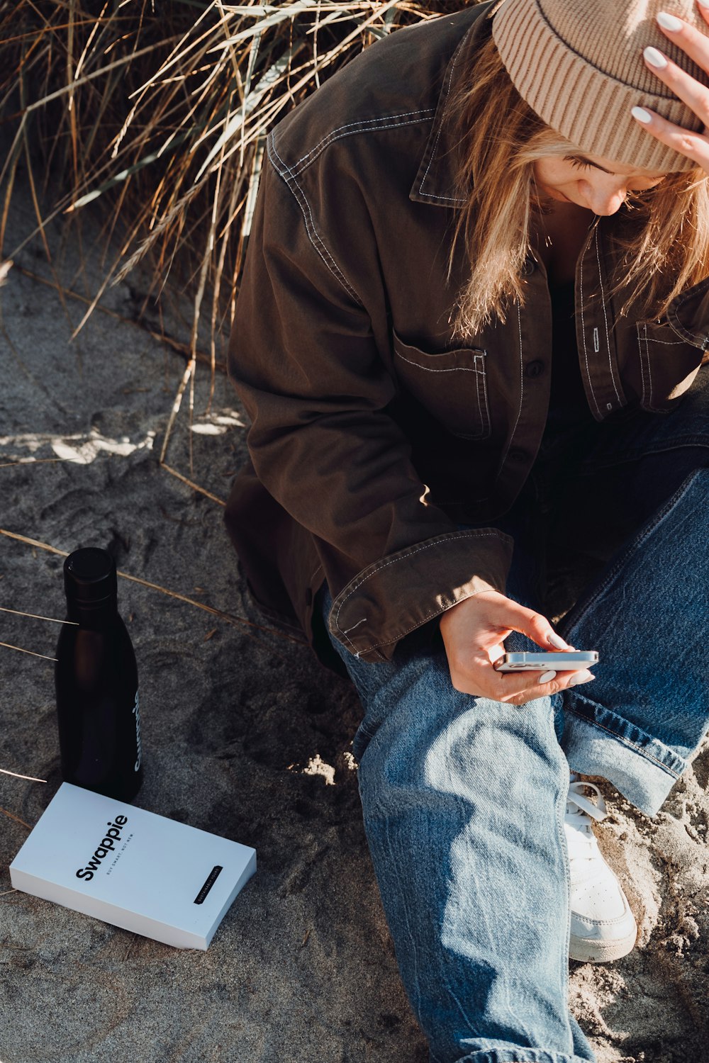Eine Person, die mit einem Handy im Sand sitzt