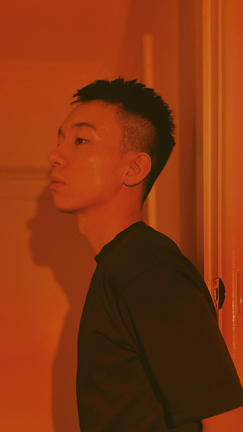 a man standing in a room with an orange wall