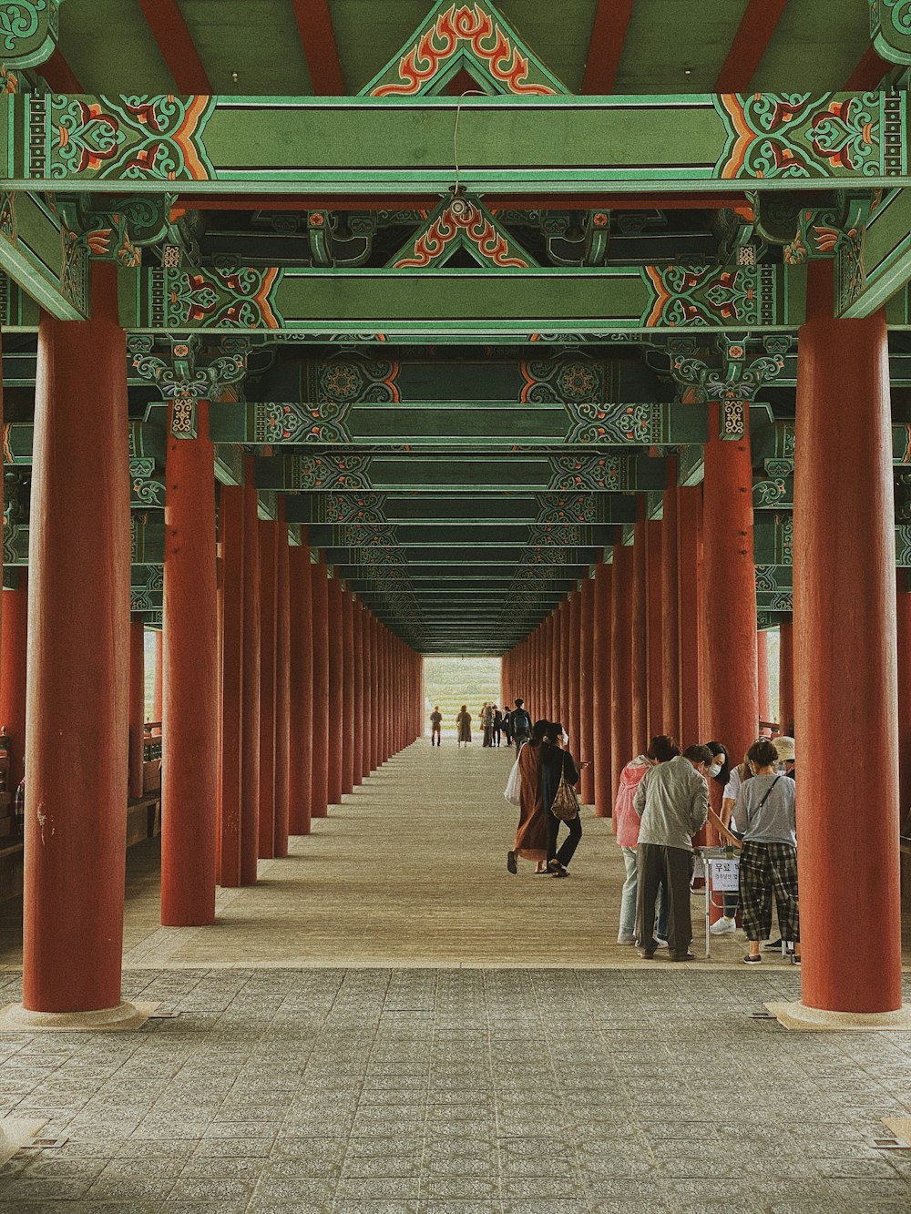 a group of people walking under a green and red structure