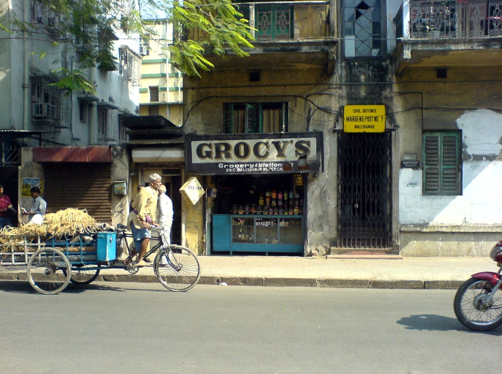 a man riding a bike down a street past a store
