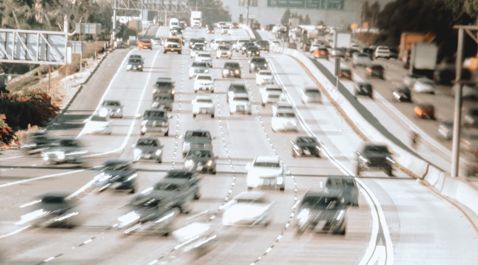 Busy highway with multiple lanes filled with cars moving at varying speeds outdoors