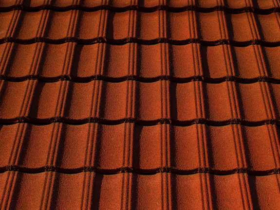 Close-up of textured terracotta roof tiles stacked neatly in sunlight.