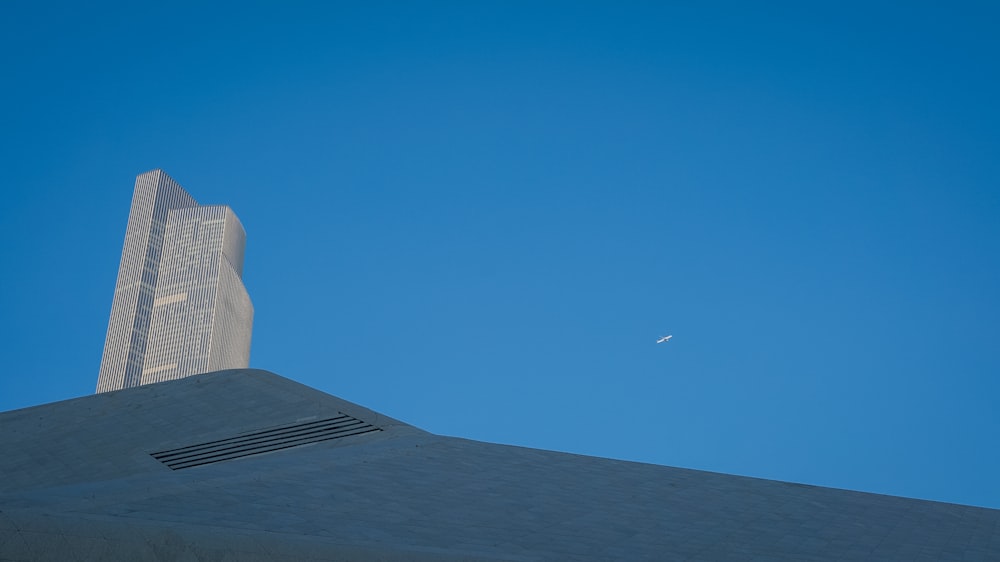 a plane flying in the sky over a tall building