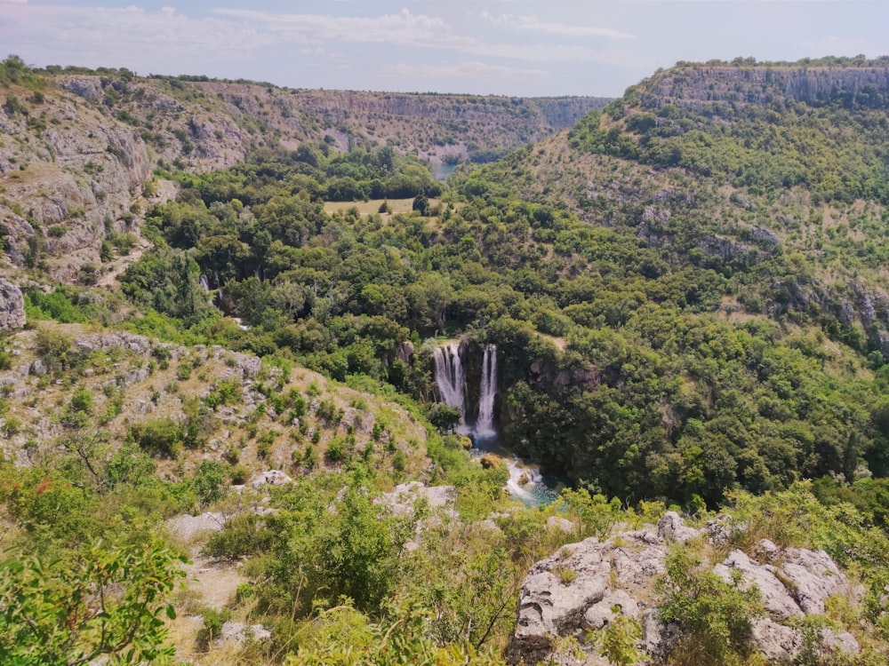 a waterfall in the middle of a lush green valley