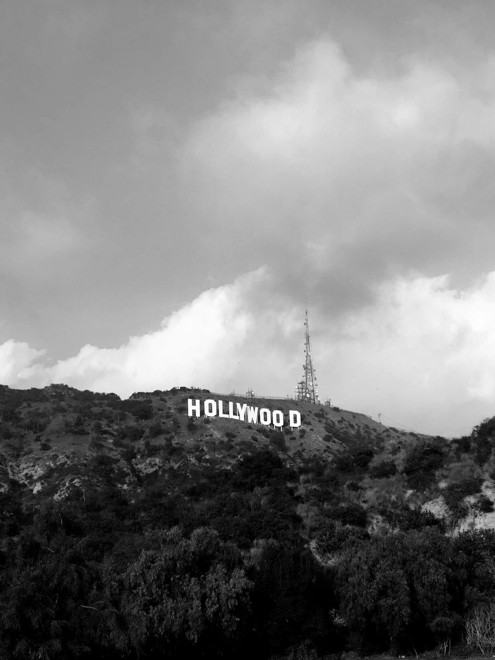 a hollywood sign on top of a mountain under a cloudy sky