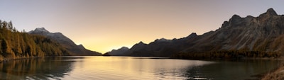 A serene lake surrounded by mountains at sunset.