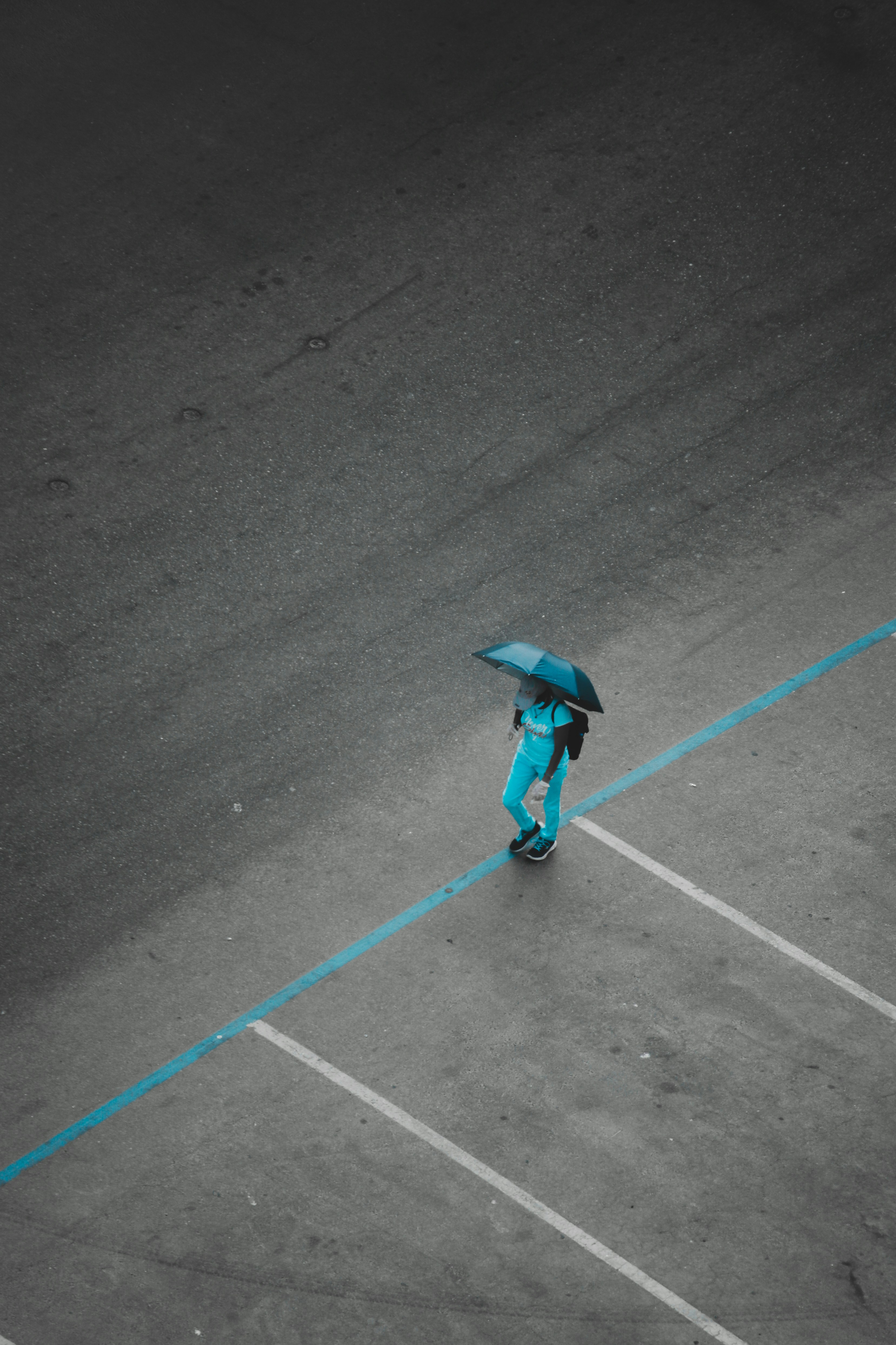 a person with an umbrella walking in a parking lot