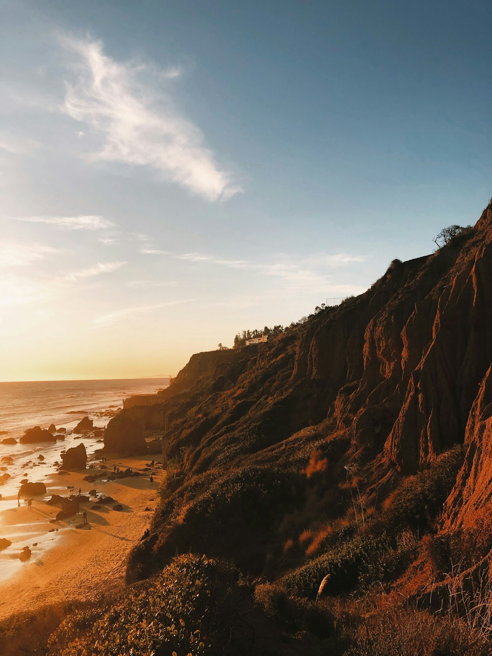 the sun is setting on a rocky beach