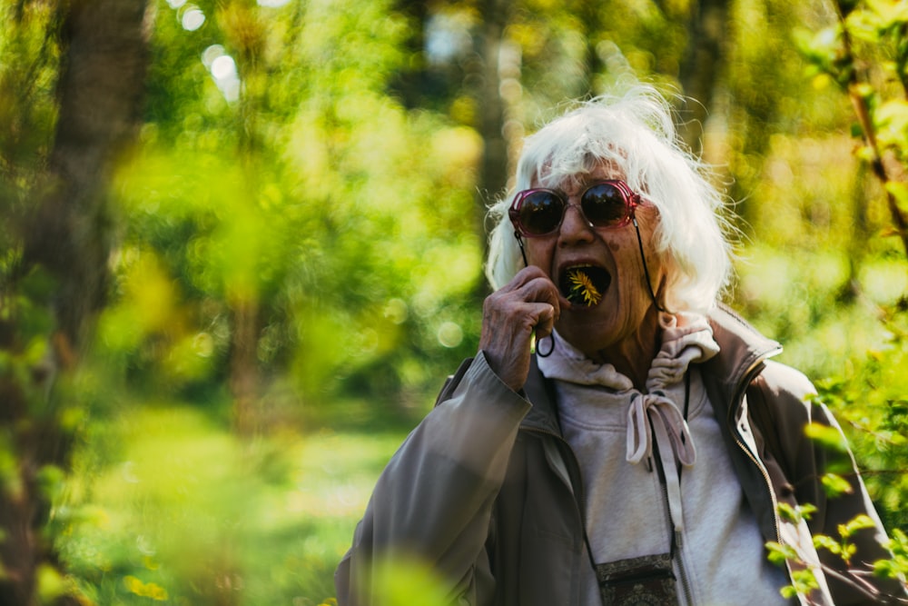 a woman with white hair and sunglasses talking on a cell phone