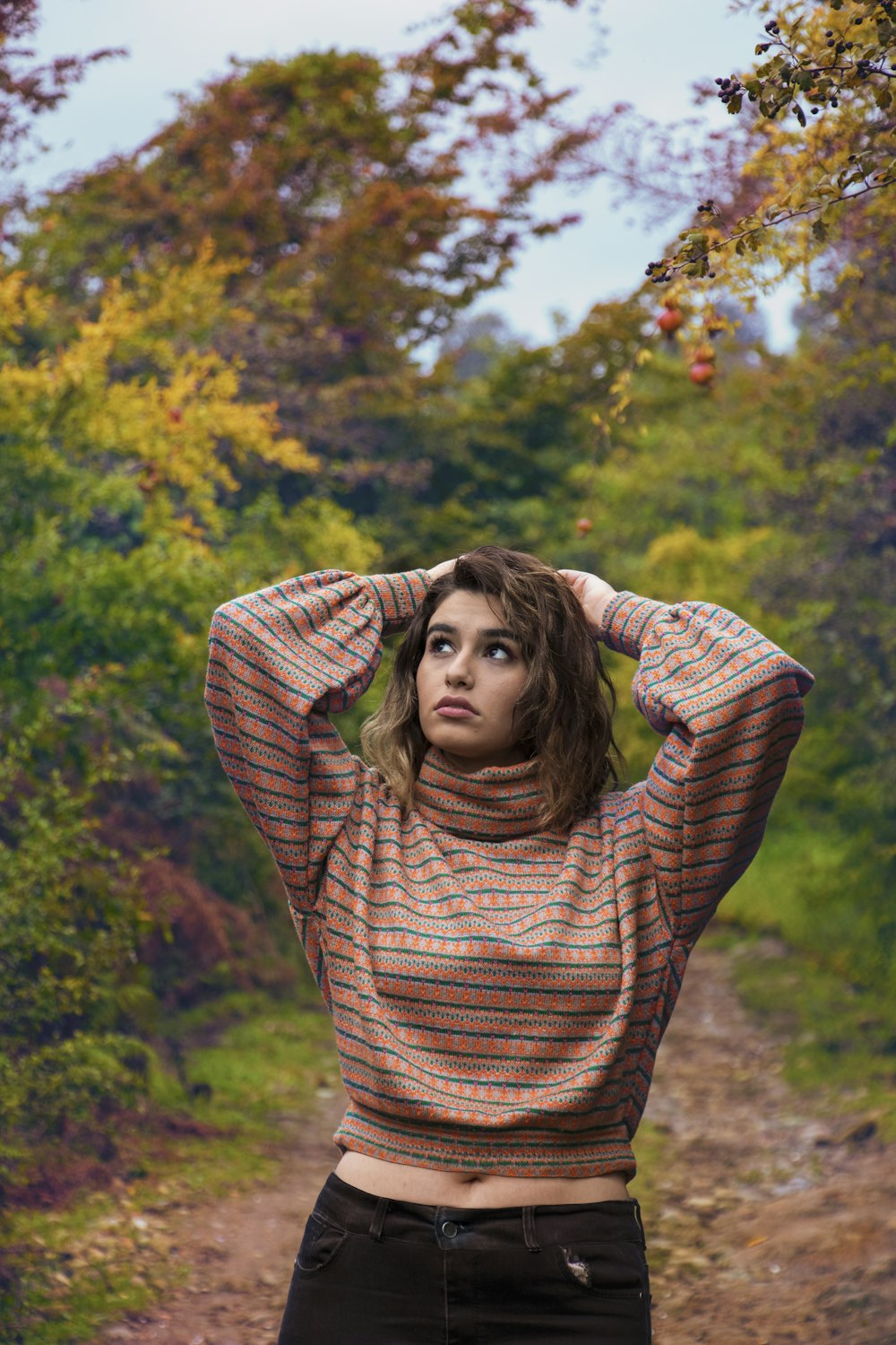 a woman standing on a dirt road with her hands on her head