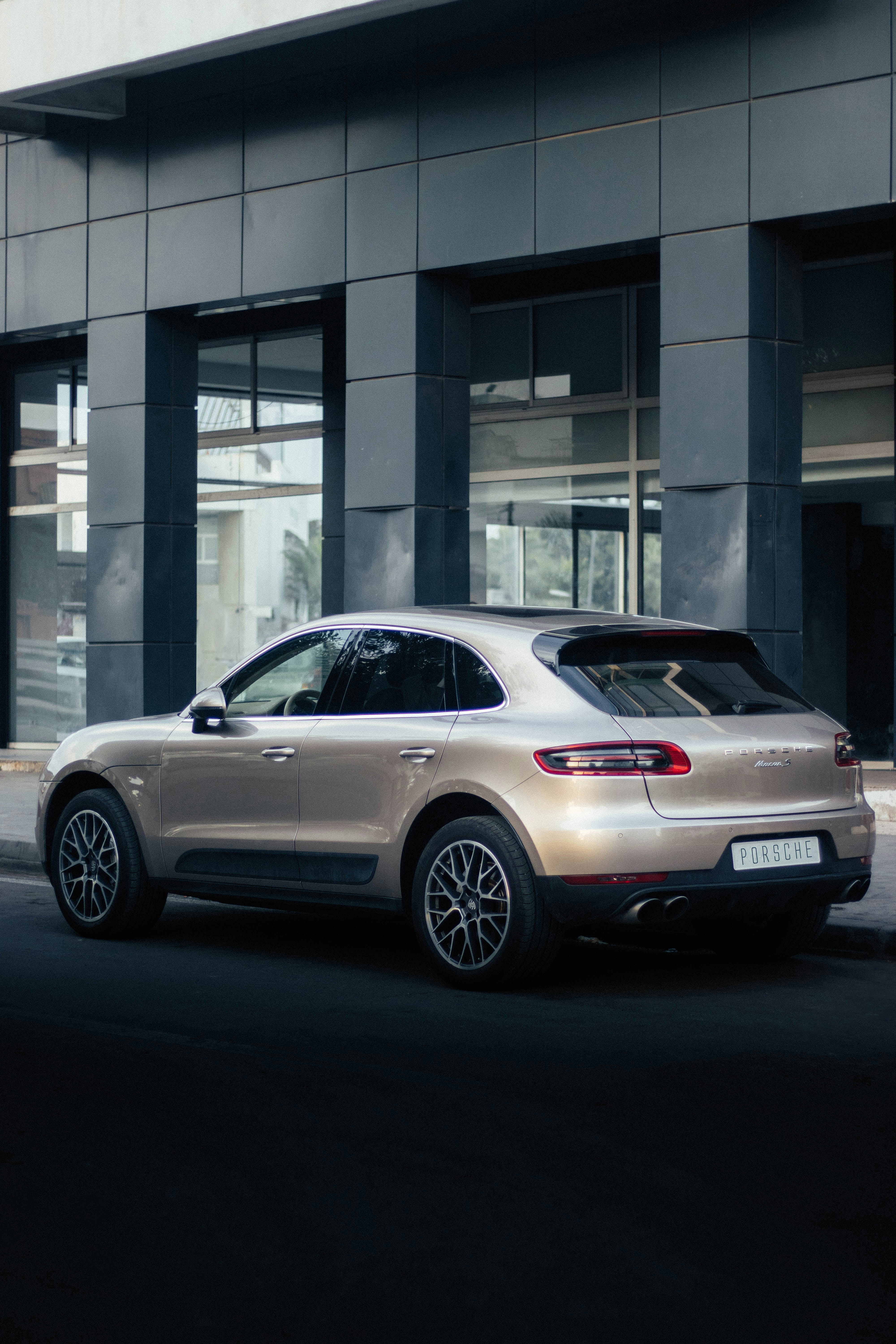 a silver porsche cayen is parked in front of a building