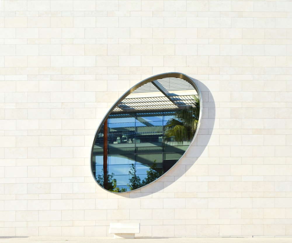 a circular mirror on a white brick wall