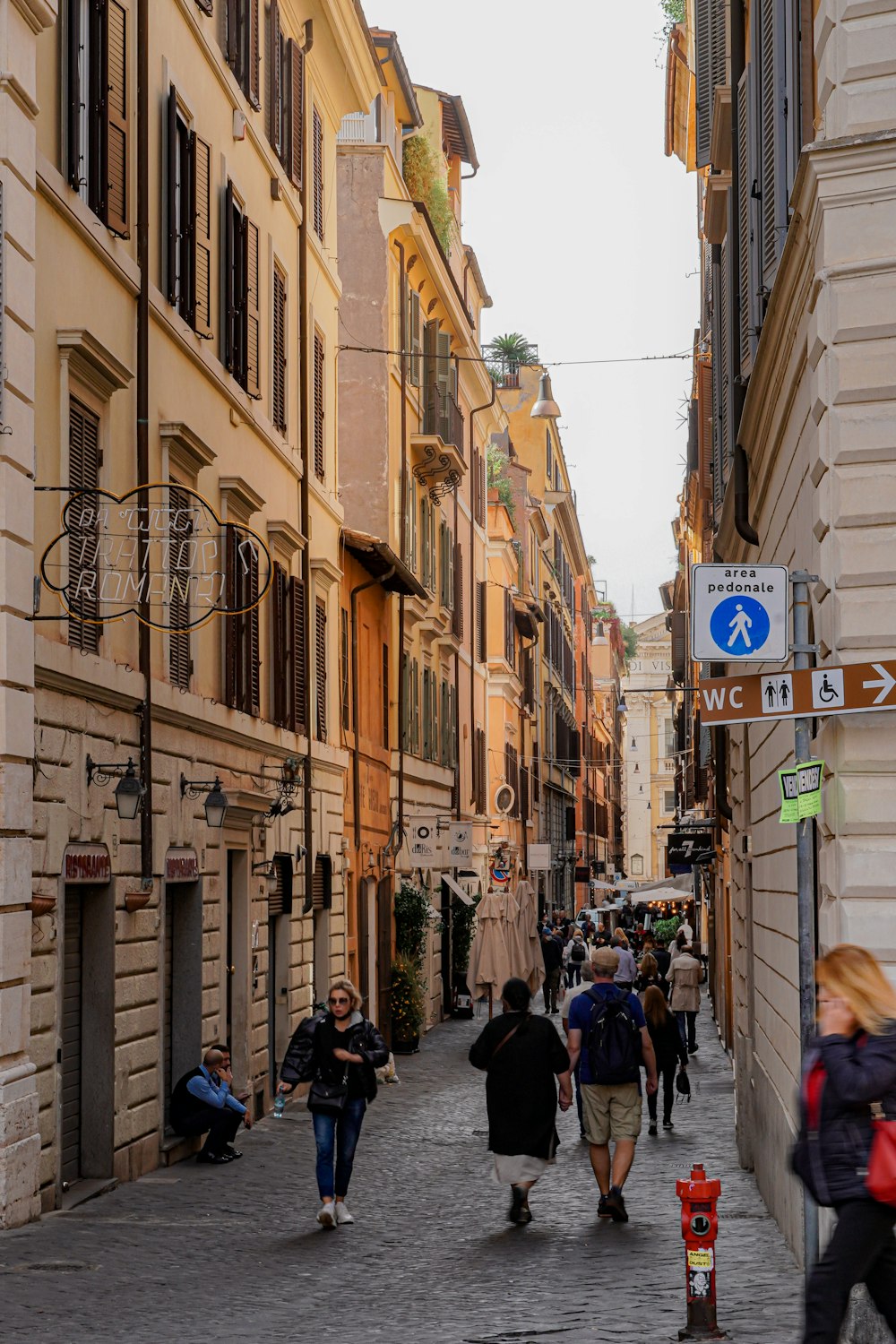 a group of people walking down a street next to tall buildings