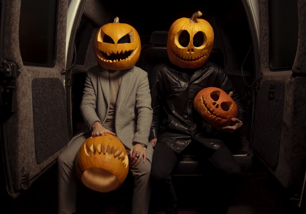 a couple of people that are sitting down with pumpkins