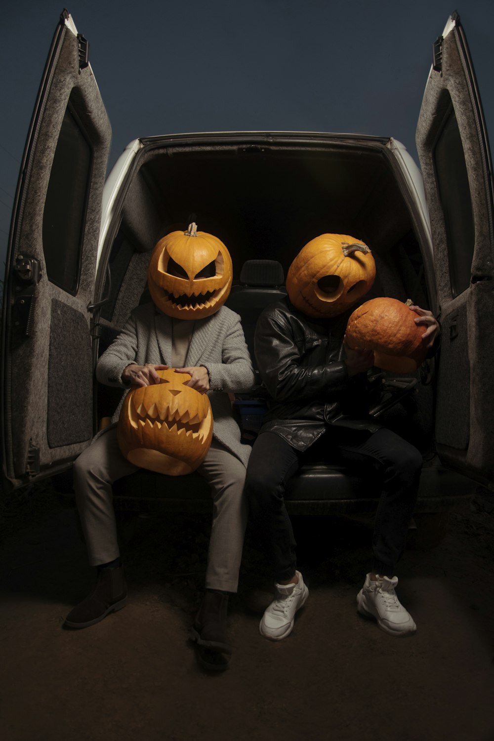 two people sitting in the back of a car with pumpkins