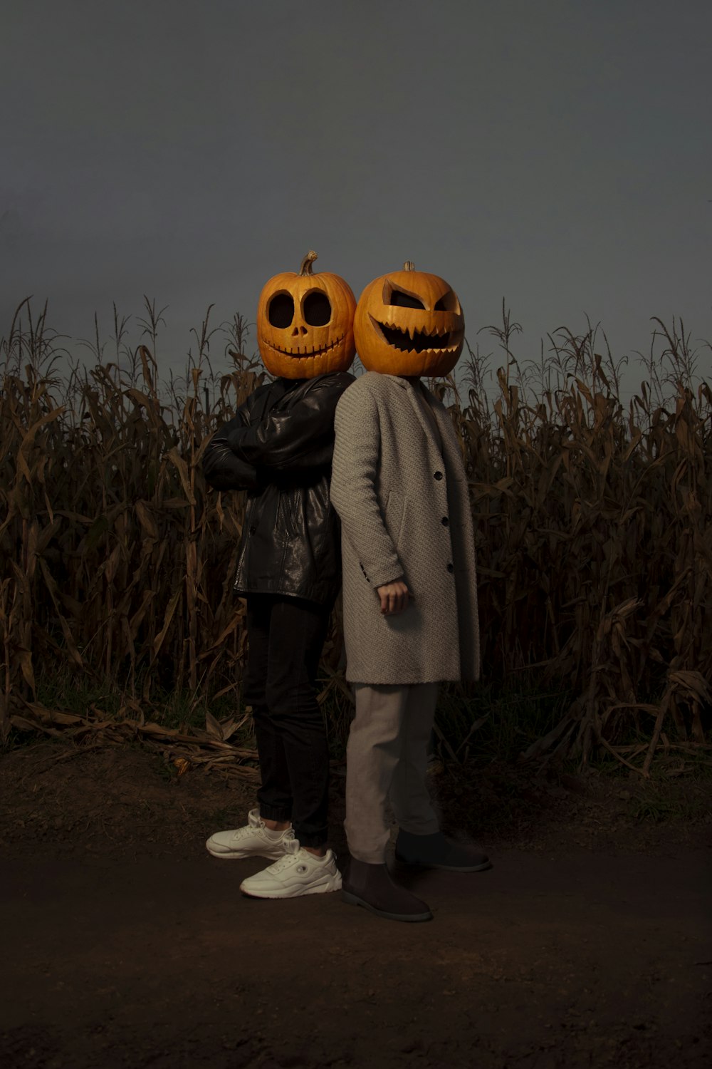 a couple of people standing next to each other in front of a corn field