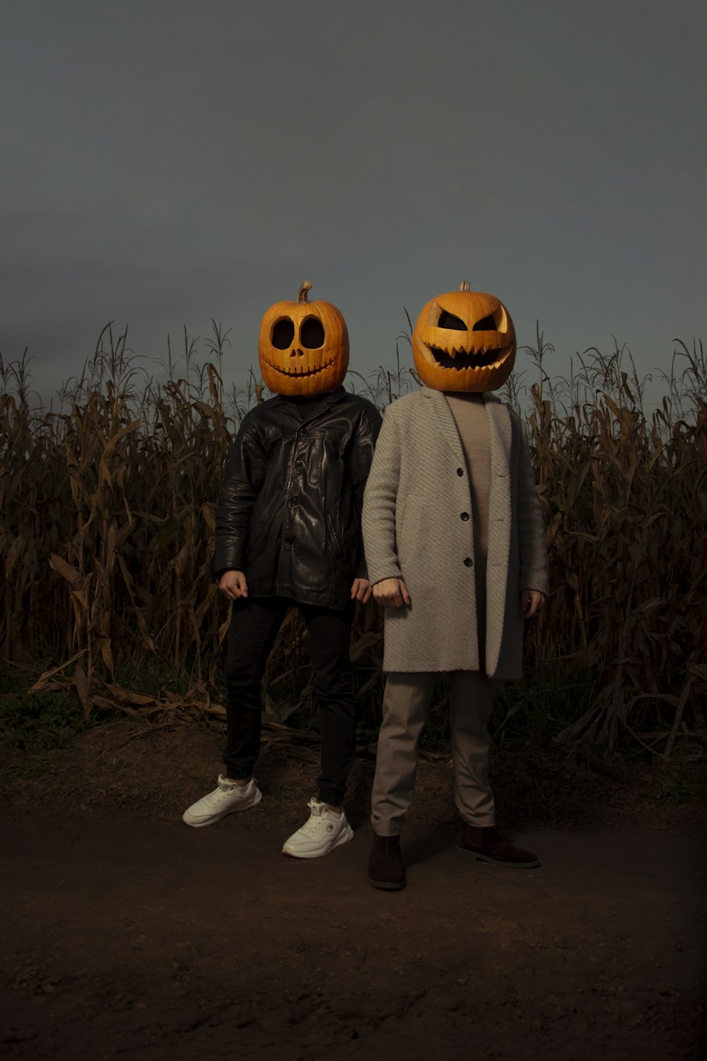 a couple of people standing next to each other wearing pumpkin heads