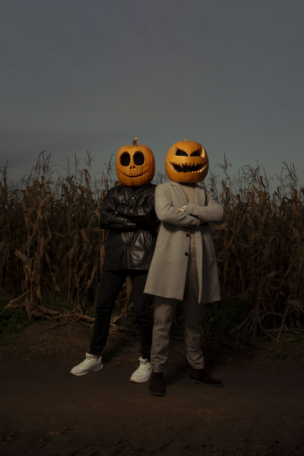 two people standing in a field with pumpkin heads on their heads
