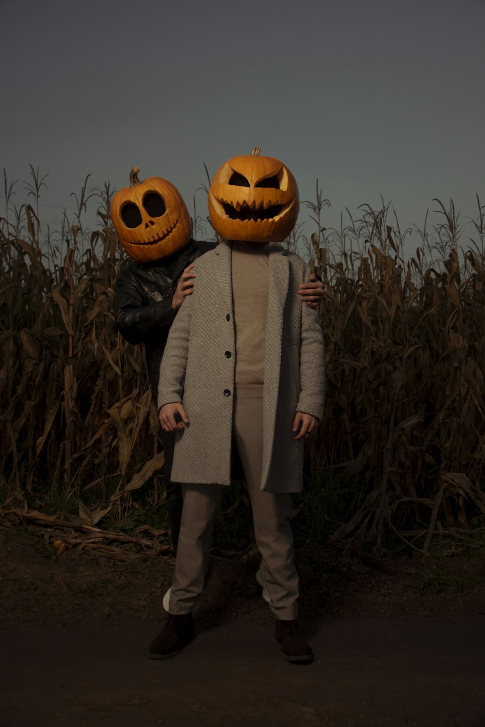 a couple of people standing in a field with pumpkins on their heads