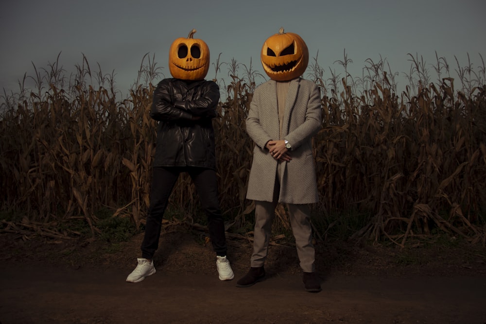 a couple of people standing next to each other in front of a corn field