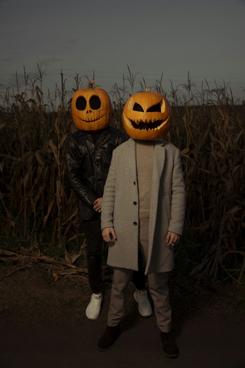 a couple of people standing in a field with pumpkins on their heads