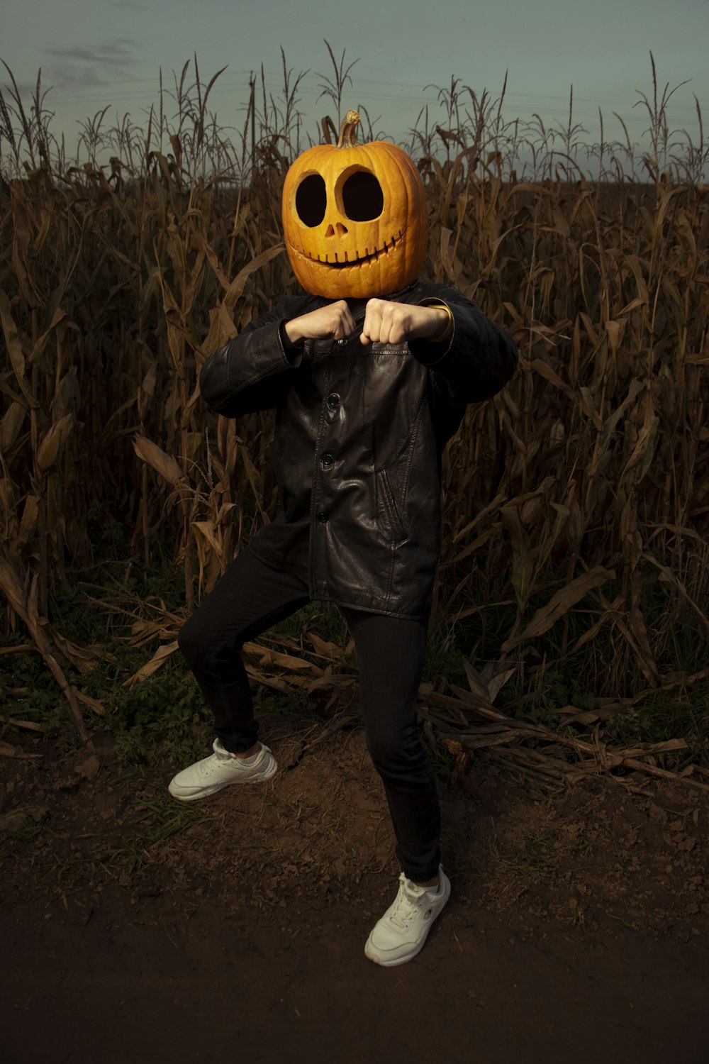 a man in a leather jacket holding a pumpkin in front of his face