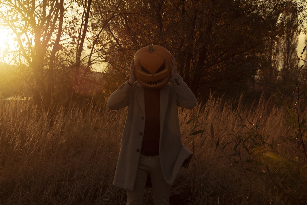 a person wearing a pumpkin mask in a field