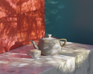 A ceramic teapot and cup sit on a marble surface. The scene is softly lit with natural light casting shadows of leaves and branches against a red and teal background, creating a tranquil atmosphere.