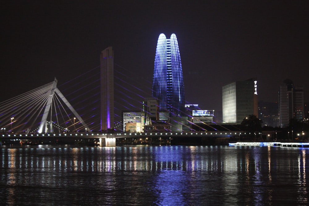 a city skyline at night with a bridge over water