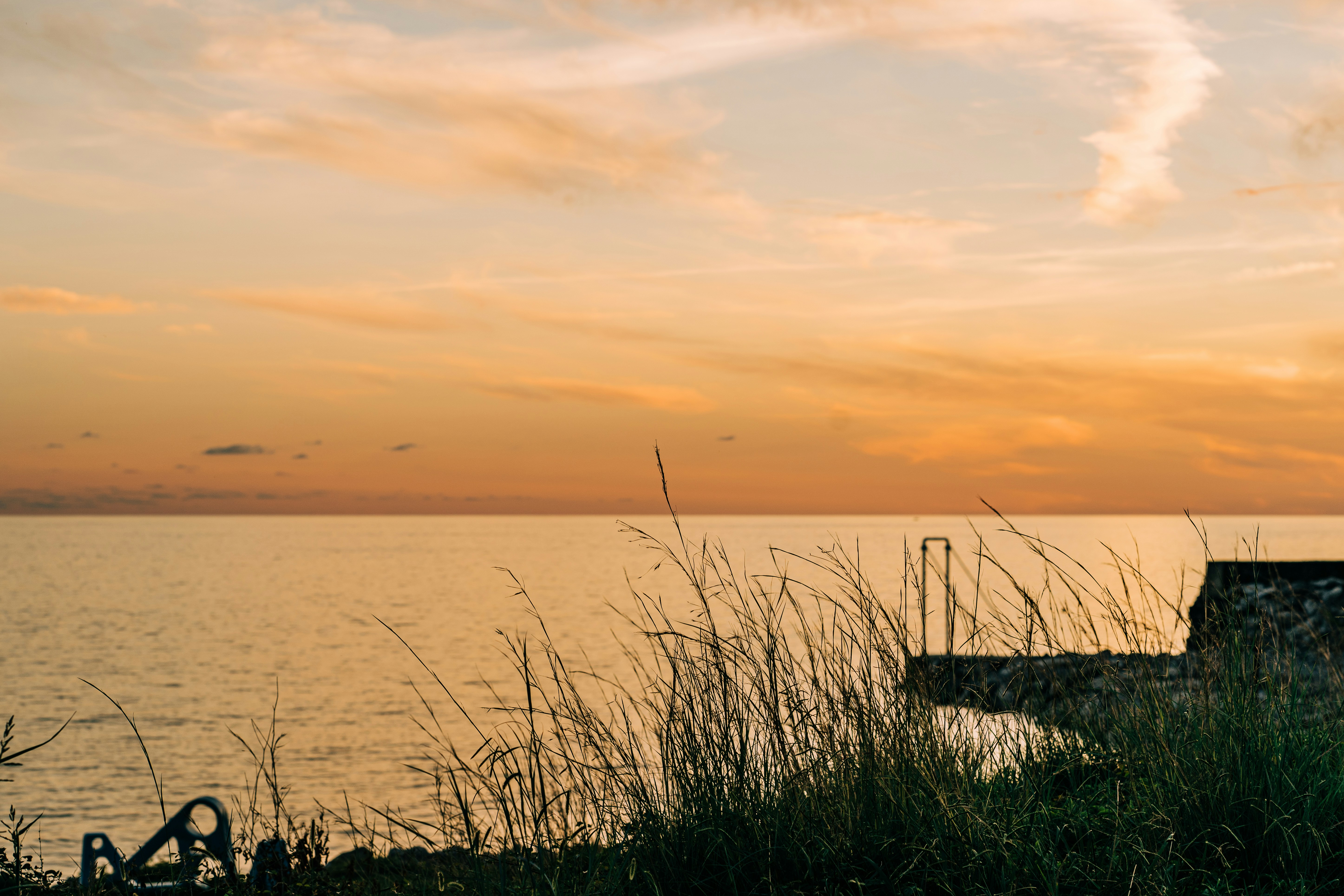 a bench sitting next to a body of water, Fall sunset in Cilento, Italy