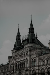 A historical building with intricate architectural details featuring arched windows, decorative stonework, and spired rooftops. The structure presents an elegant and ornate design, characterized by its large, pointed towers and a mix of geometric patterns on its facade.