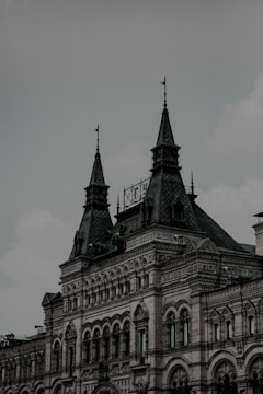 A historical building with intricate architectural details featuring arched windows, decorative stonework, and spired rooftops. The structure presents an elegant and ornate design, characterized by its large, pointed towers and a mix of geometric patterns on its facade.