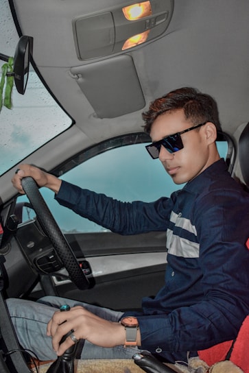 Young driver smiling confidently behind the wheel during a sunny driving lesson.