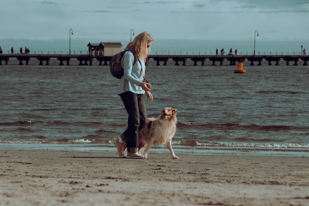 a woman walking her dog on the beach