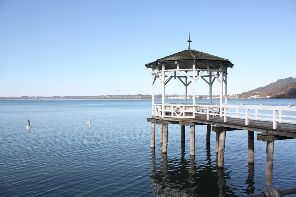 a gazebo sitting on top of a pier next to a body of water