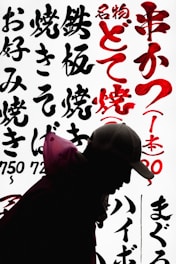 Close-up of a black hoodie with bold red Japanese-inspired graphics on a gritty urban background.