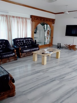 A spacious living room with marble flooring and modern decor.