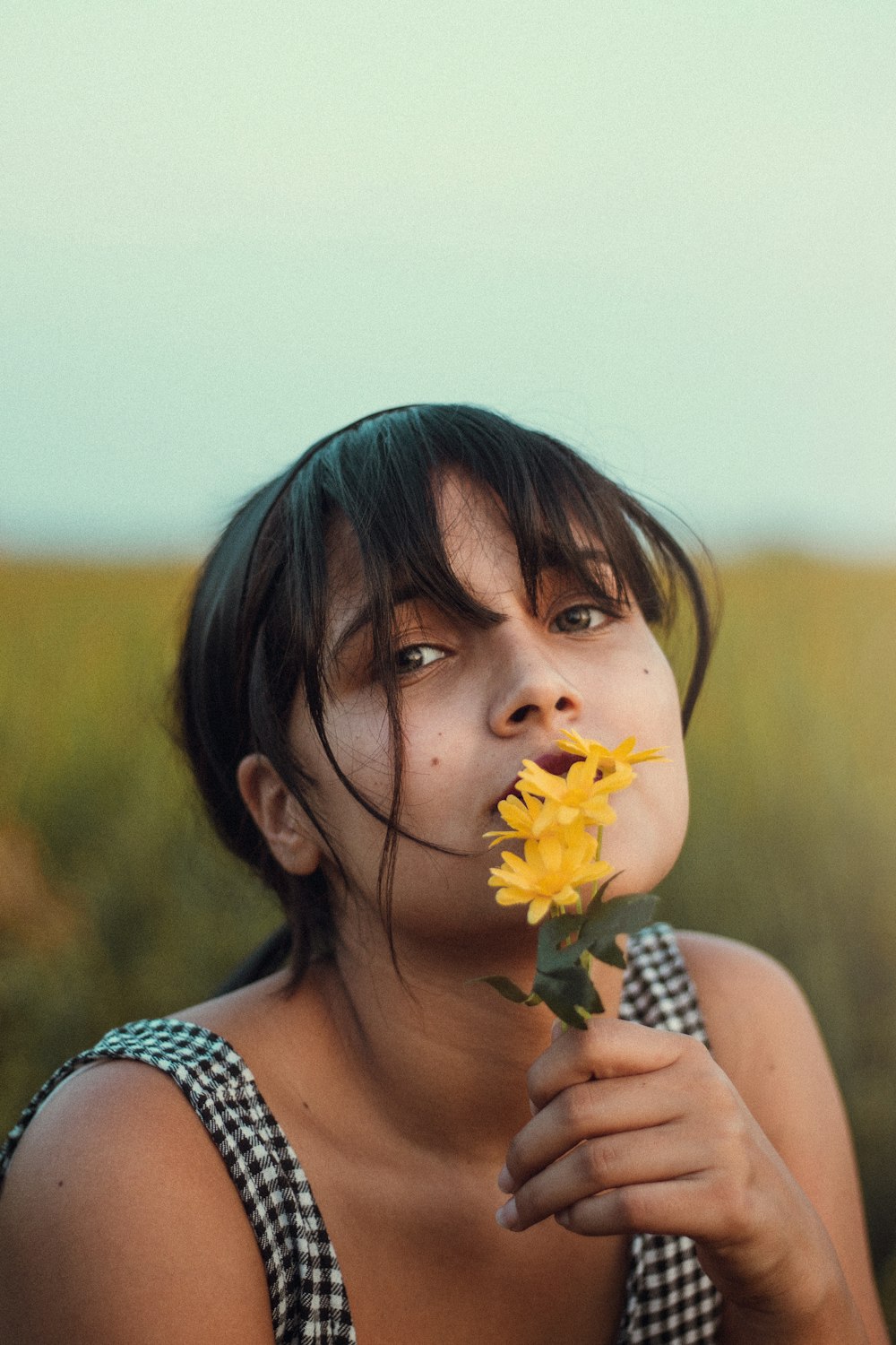 a woman holding a yellow flower in her mouth