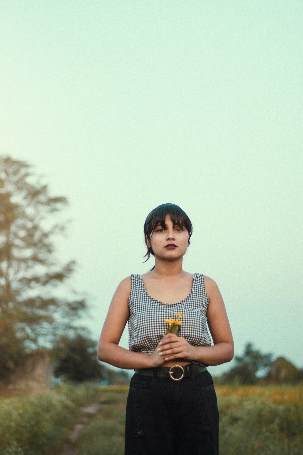 a woman standing in the middle of a dirt road