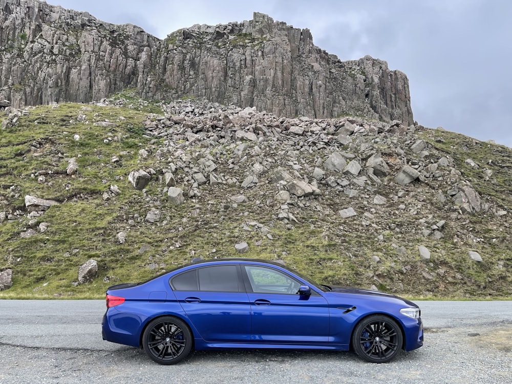 a blue car parked in front of a mountain