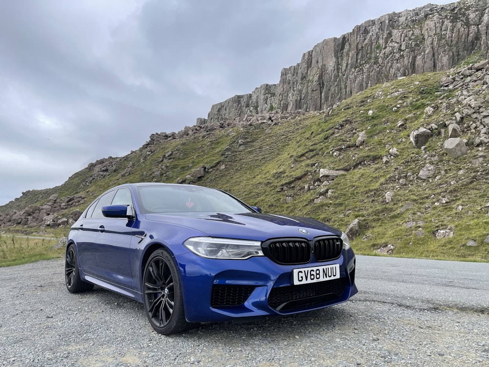 a blue car parked in front of a mountain