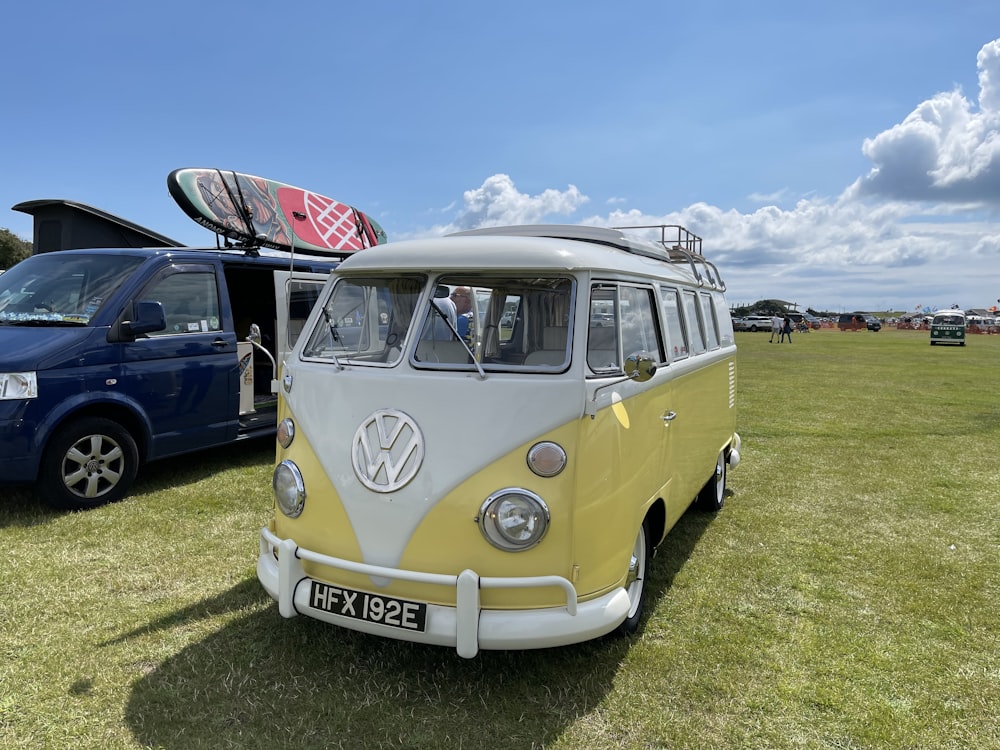 a yellow and white vw bus parked next to a blue van